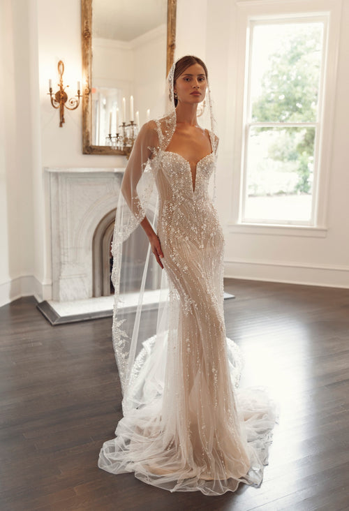 Julie Vino Stella 3204 fitted wedding dress with a plunging neckline, floral beadwork and embellished straps, styled with a sheer veil.