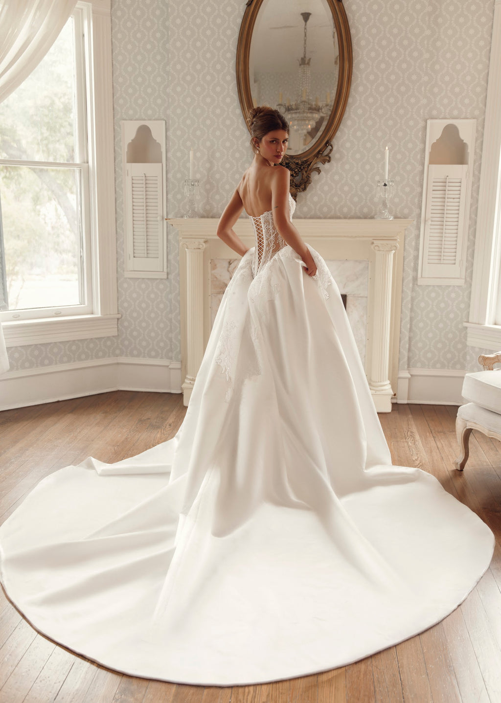Back view of Julie Vino Valeria 3211 wedding dress showing a sheer lace-up corset, full skirt and broad sweeping train.