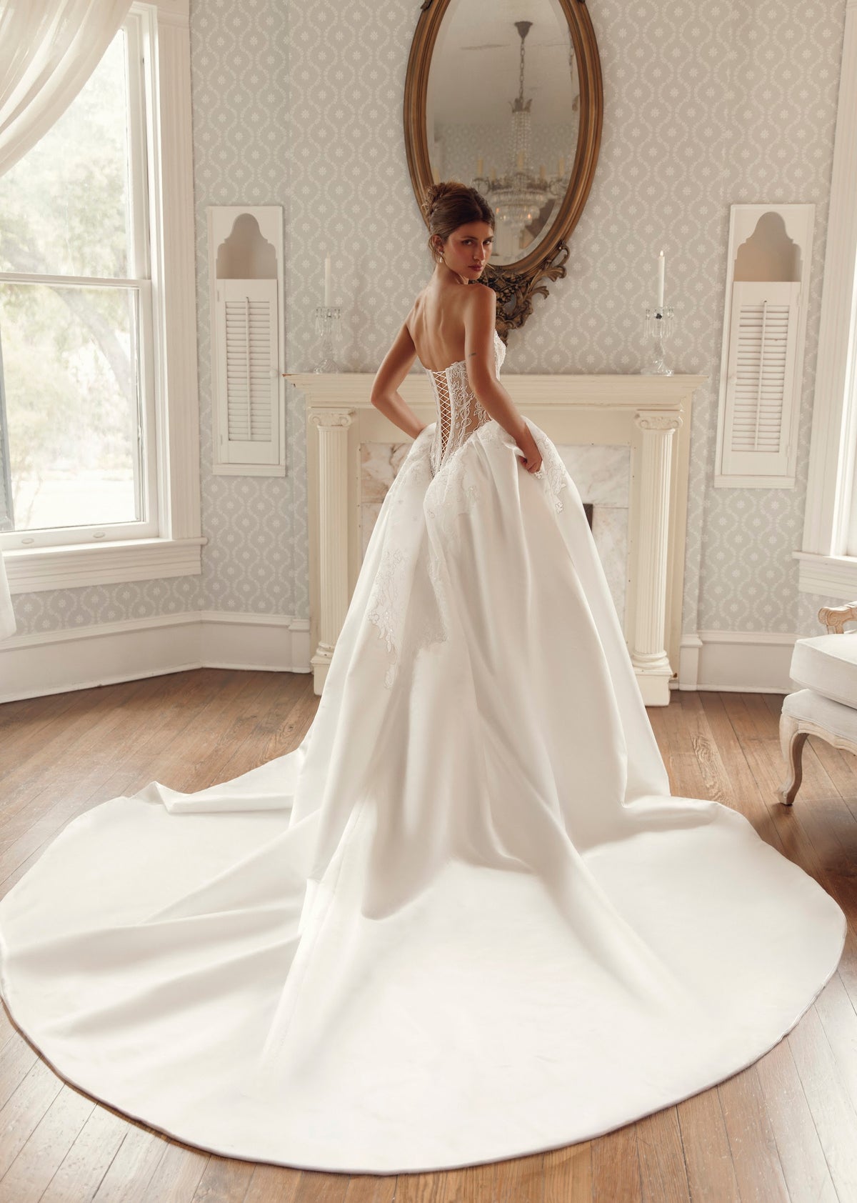 Back view of Julie Vino Valeria 3211 wedding dress showing a sheer lace-up corset, full skirt and broad sweeping train.