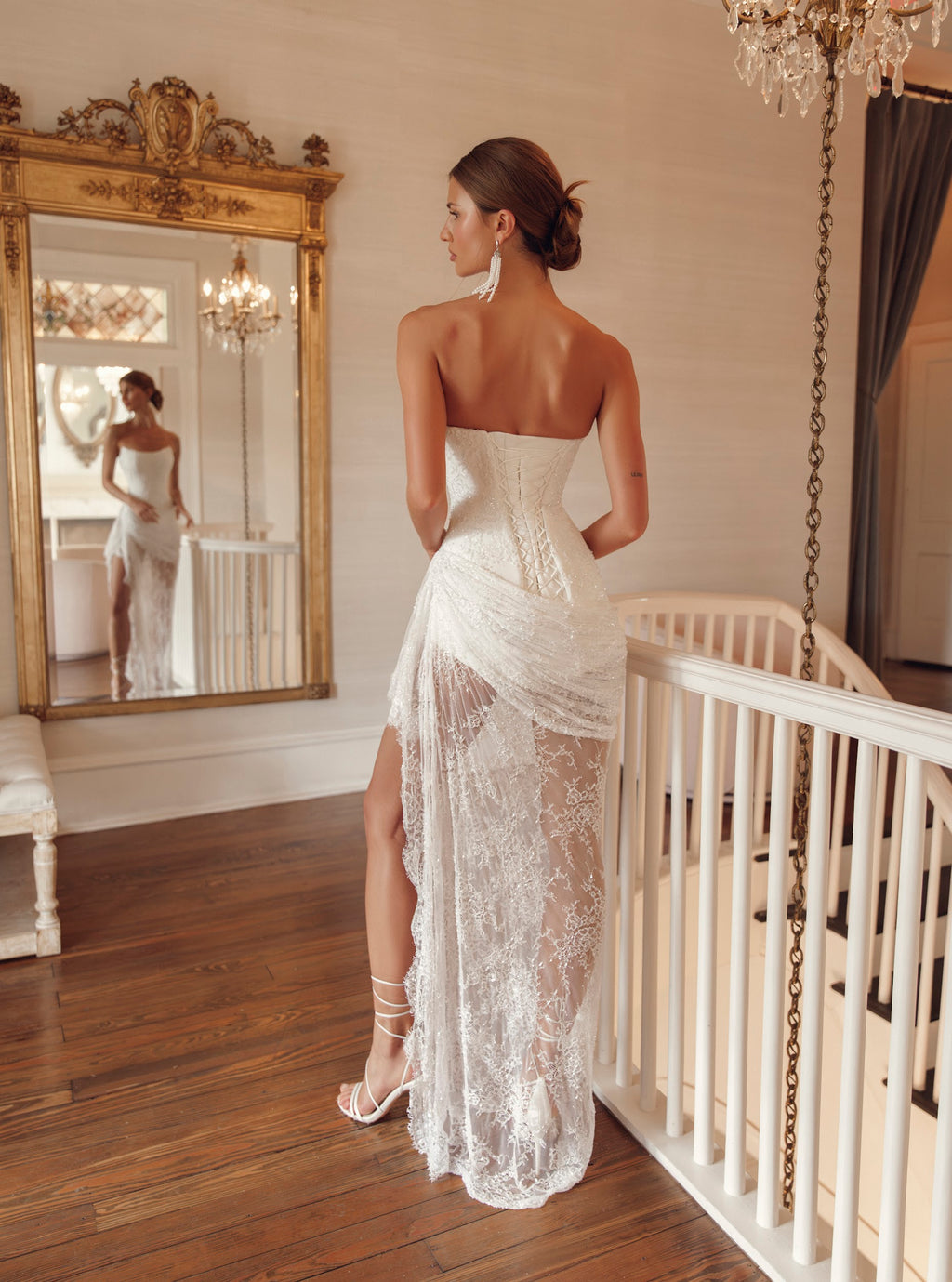 Back view of Julie Vino Yasmin 3212 wedding dress showing an elongated lace-up corset, gathered hip draping and a sheer floral lace skirt.