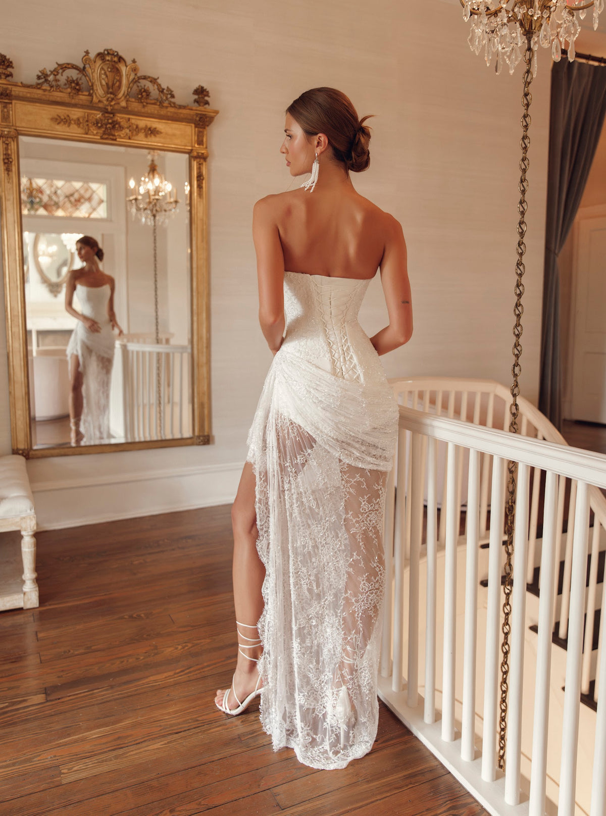 Back view of Julie Vino Yasmin 3212 wedding dress showing an elongated lace-up corset, gathered hip draping and a sheer floral lace skirt.