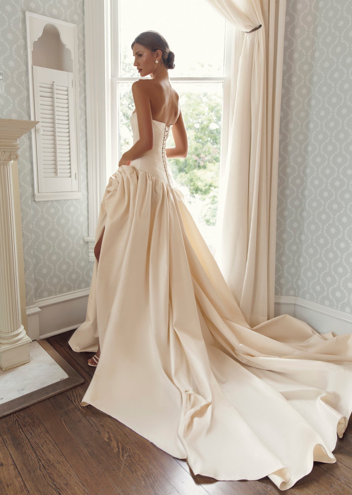 Back view of Julie Vino Casandra 3213 wedding dress showing a lace-up corset, asymmetric dropped waist and full skirt with a long sweeping train.