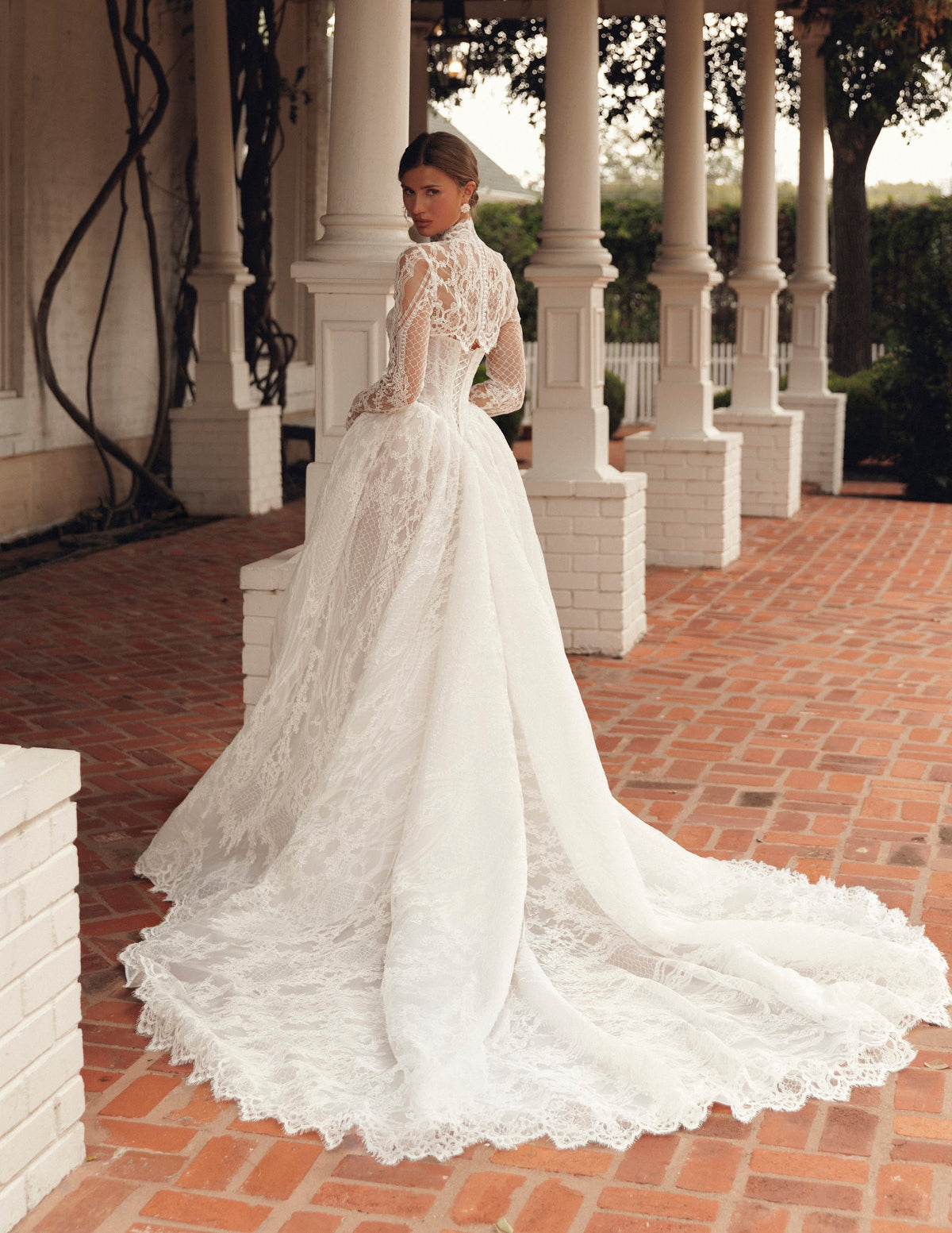 Mimosa by Julie Vino Jolie MB27-21 wedding dress showing a pointed corset waist, full lace skirt and coordinating long-sleeve lace topper.