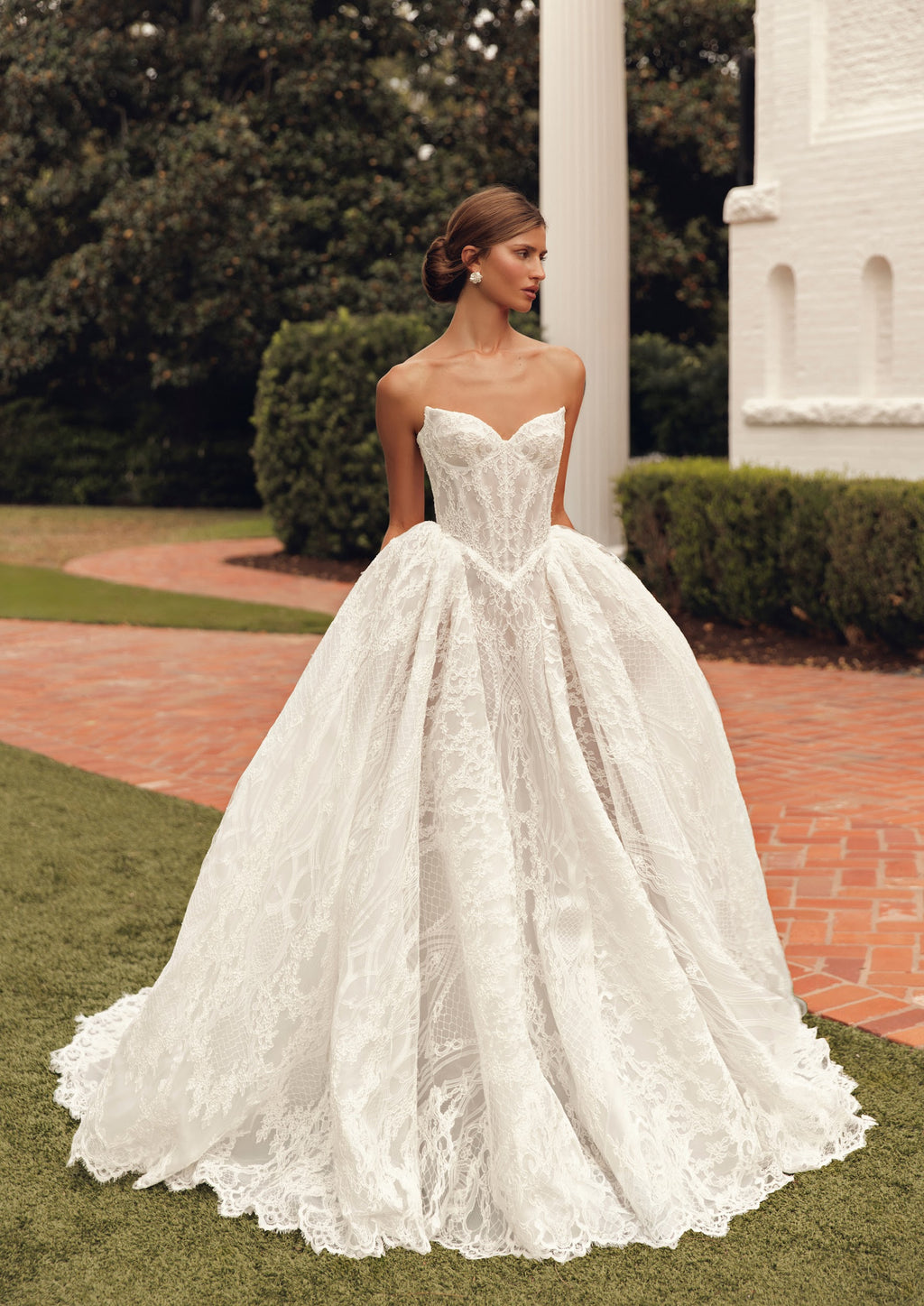 Mimosa by Julie Vino Jolie MB27-21 wedding dress showing a pointed corset waist, full lace skirt and coordinating long-sleeve lace topper.