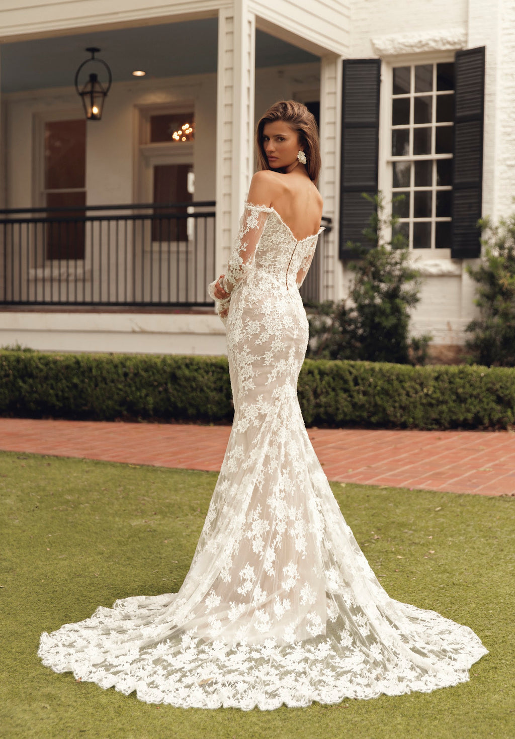 Side-back view of Mimosa by Julie Vino Petra MB27-23 lace wedding dress with long sleeves and a scalloped train, styled with a lace-edged veil.