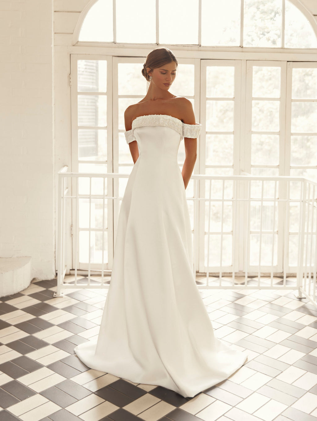 Front detail of Mimosa by Julie Vino Ophelia MB27-24 wedding dress with floral lace neckline trim, off-shoulder sleeves and a smooth fitted bodice.