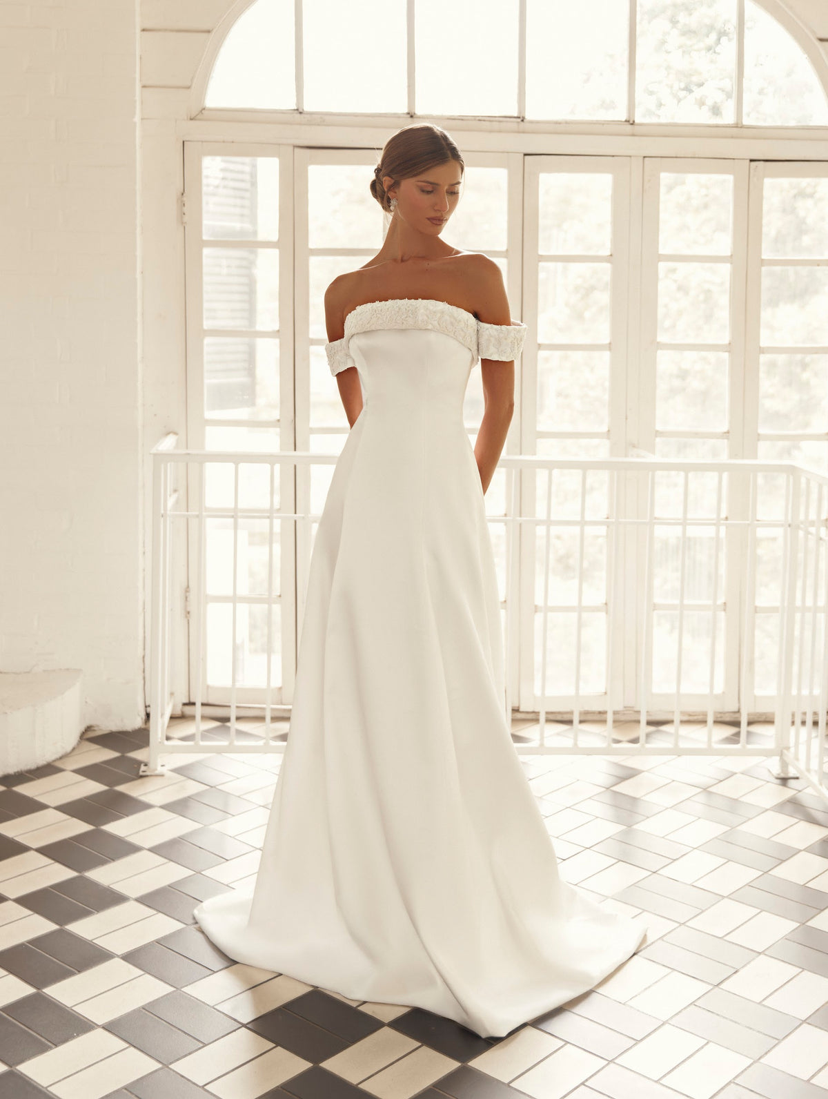 Front detail of Mimosa by Julie Vino Ophelia MB27-24 wedding dress with floral lace neckline trim, off-shoulder sleeves and a smooth fitted bodice.