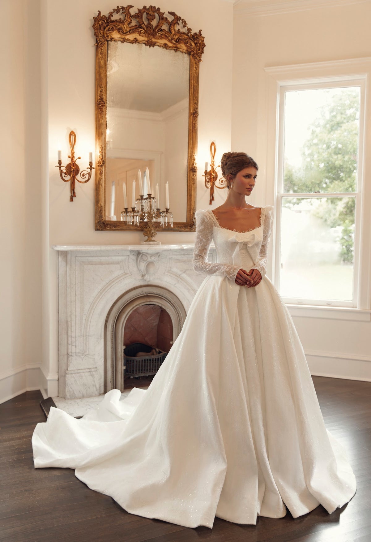 Front view of Mimosa by Julie Vino Nicoletta MB27-27 ball gown wedding dress with long illusion lace sleeves, a square neckline and statement bow.