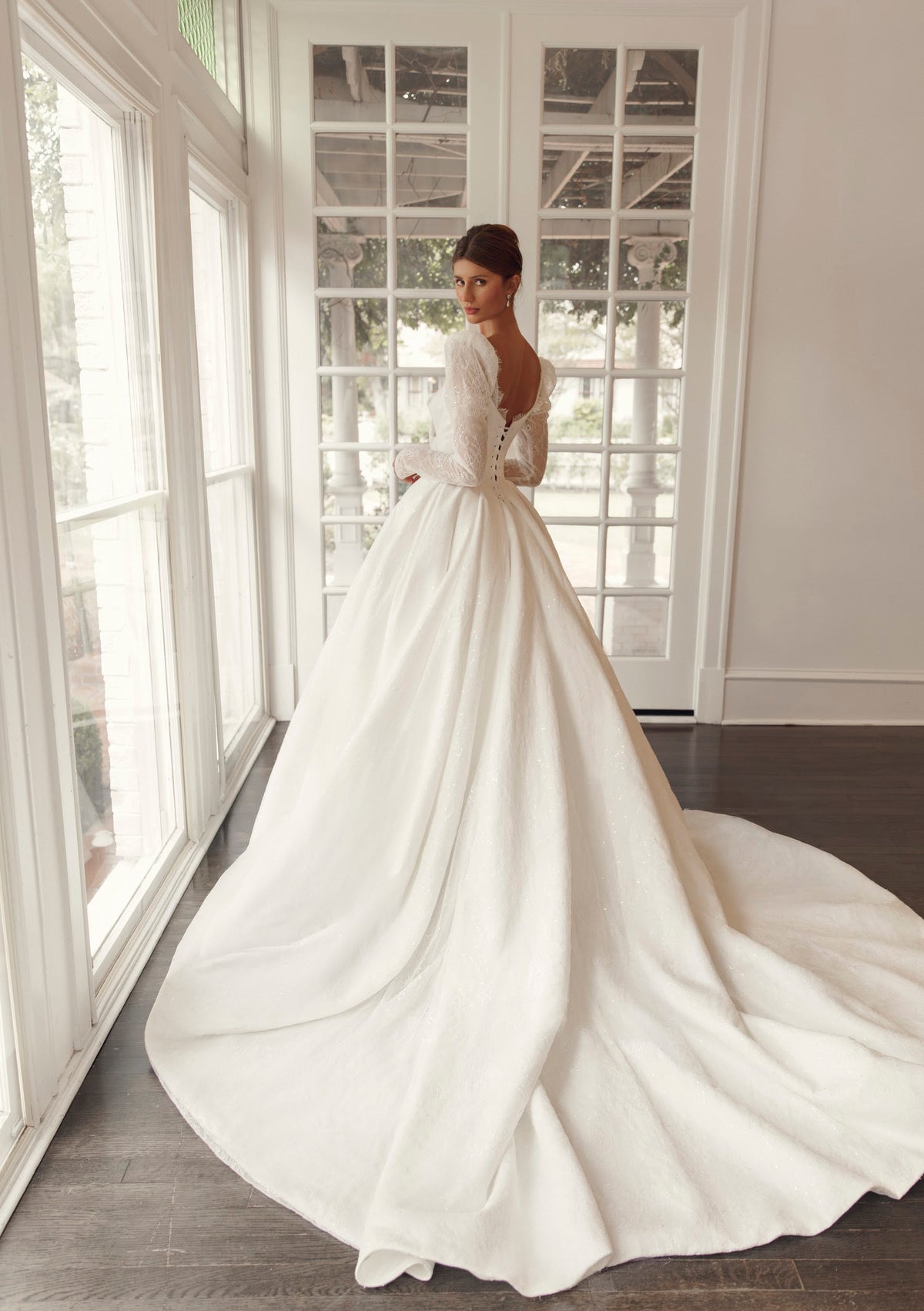 Back view of Mimosa by Julie Vino Nicoletta MB27-27 wedding dress with a low rounded back, lace-up corset and full skirt flowing into a long train.