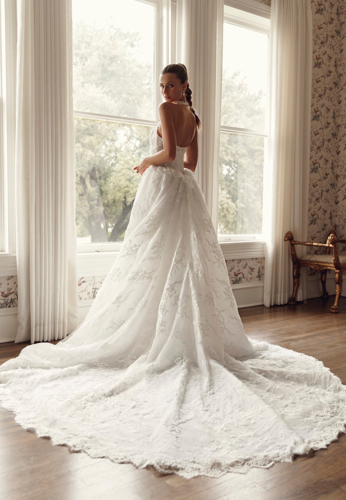 Back view of Mimosa by Julie Vino Avianna MB27-29 showing an open halter back and a voluminous lace overskirt with a sweeping train.