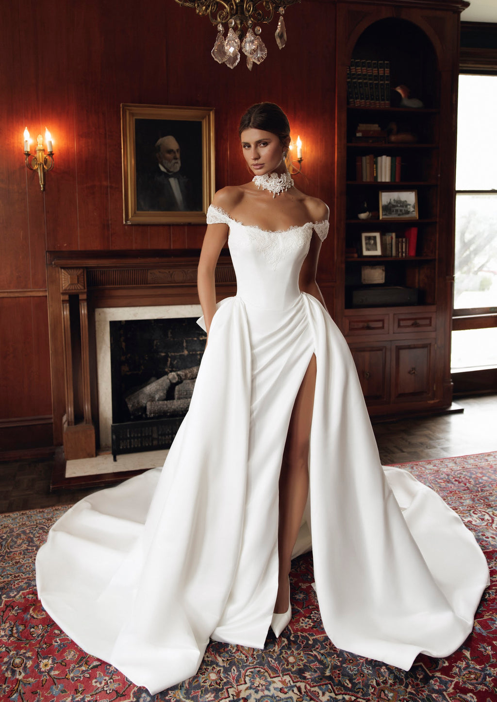 Estelle PR27-23 by Pure by Julie Vino, showing the lace off-the-shoulder neckline, draped skirt and high slit, styled with a full overskirt.