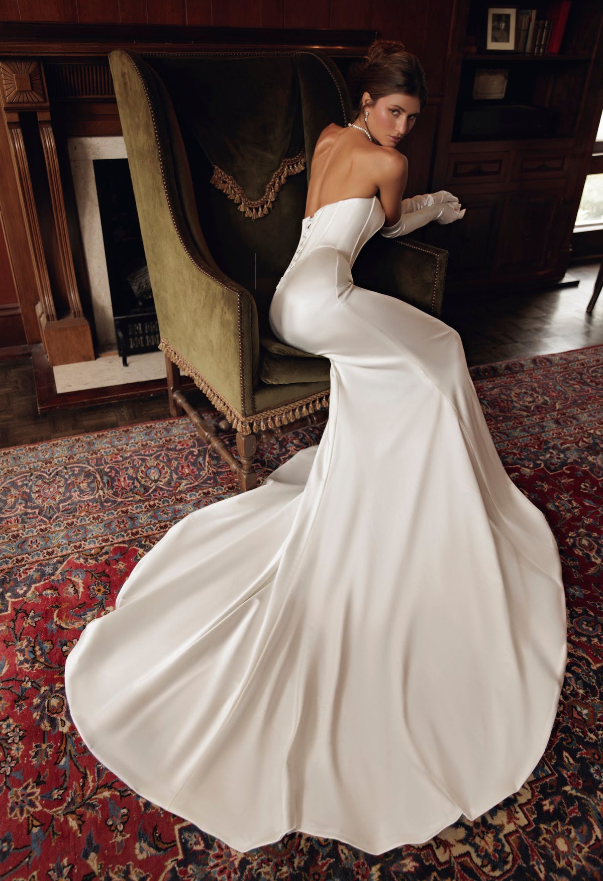 Seated back view of Romy PR27-31 by Pure by Julie Vino, showing the low strapless neckline, corset lacing and smooth flowing train.