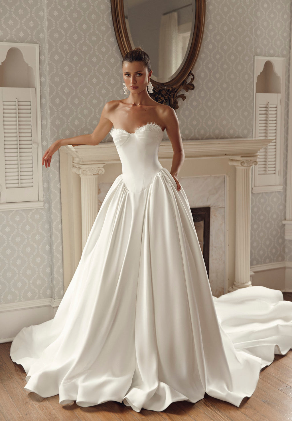 Seated back view of Iliana PR27-32 by Pure by Julie Vino, showing the low strapless bodice, corset lacing and full skirt spreading into a sweeping train.
