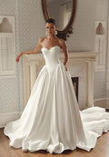 Seated back view of Iliana PR27-32 by Pure by Julie Vino, showing the low strapless bodice, corset lacing and full skirt spreading into a sweeping train.
